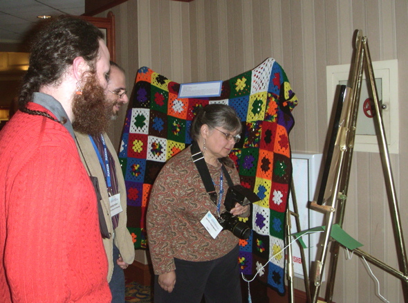 Jake Wildstrom, Josh Holden, and Dorothy Yacek-Matulis examine Mary Shepherd's cross stitch