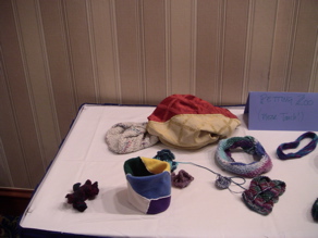 Closeup of the left half of the petting zoo: left to right, a piece of hyperbolic space, a seven-colored flat fleece torus, a nonorientable surface of genus 3, a Fortunatus' purse, three small bits of hyperbolic surface, a Klein bottle, a braid, and a Mobius band.